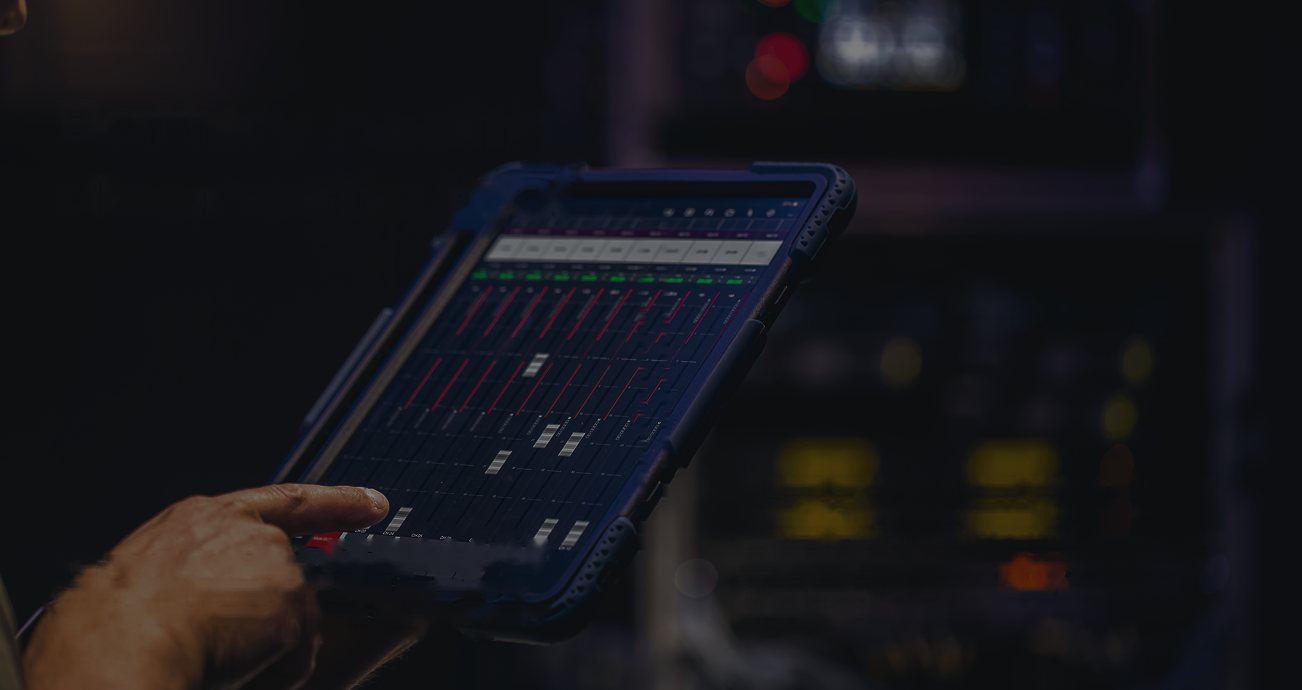 Technician tapping a rugged tablet that shows battery diagnostic bars in a dim workshop